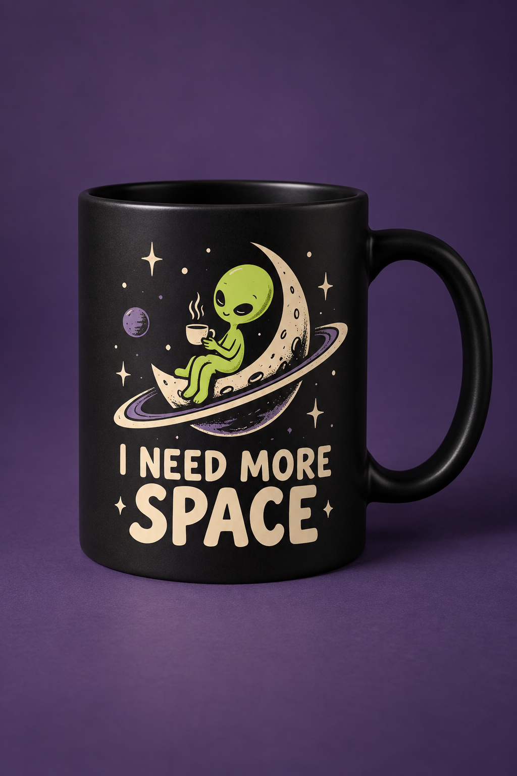 Matte black mug with an original sleepy alien sitting on a ringed planet and the words I Need More Space
